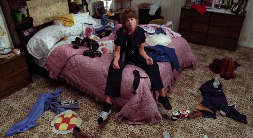 woman in police uniform sits listlessly on bed in messy room; Holly Hunter in Raising Arizona