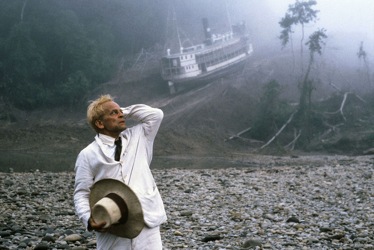 a white man in a white suit looks distressed in front of a riverboat stuck on the side of a mountain; Klaus Kinski in Werner Herzog's Fitzcarraldo